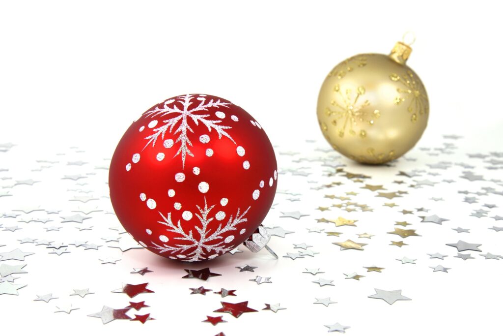 two Christmas baubles resting on a background of gold and red stars